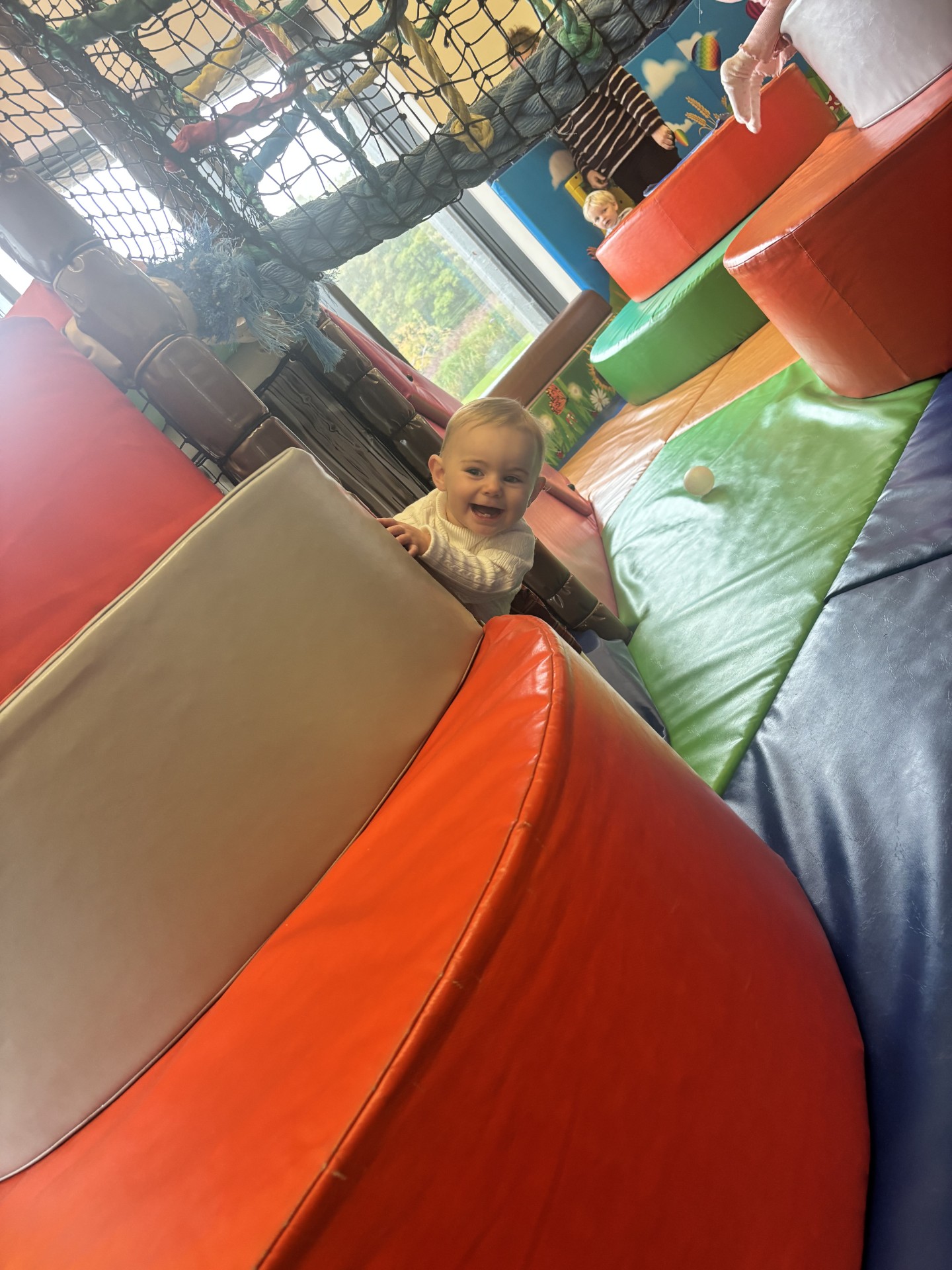 Happy baby climbing on colourful soft play blocks